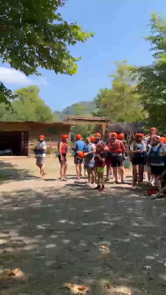 Melen Çayı kıyısında kurumsal rafting organizasyonu için kask ve can yeleğiyle sıra olan büyük katılımcı grubu