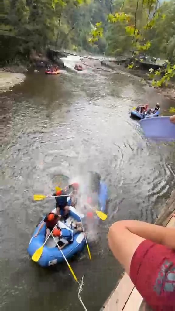 Düzce rafting parkurunda geniş nehir yatağında dönüş manevrası yapan mavi bot ve kırmızı can yelekli ekip