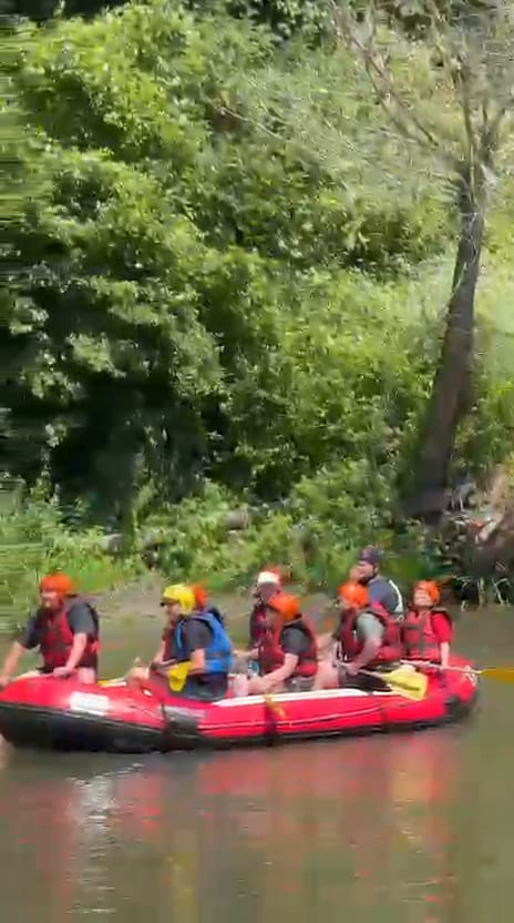 Melen Çayı rafting parkurunda ağaçlarla kaplı kıyı boyunca süzülen bot ve can yeleği giymiş katılımcılar