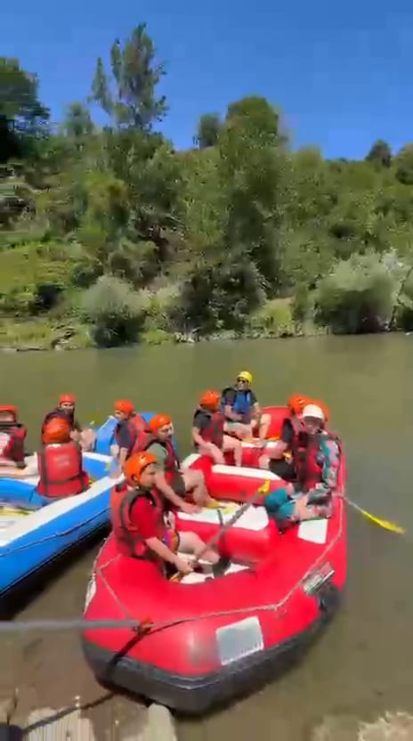Melen Çayı kıyısında mavi bota yerleşen turuncu kasklı rafting katılımcıları