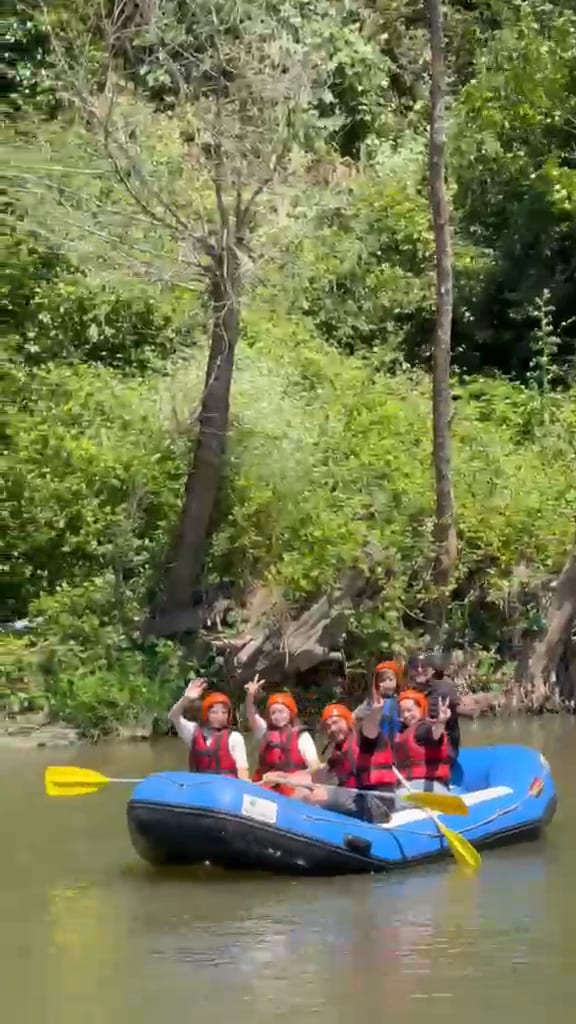 Melen Çayı rafting parkuru başlangıcında botta el sallayan turuncu kasklı katılımcı grubu