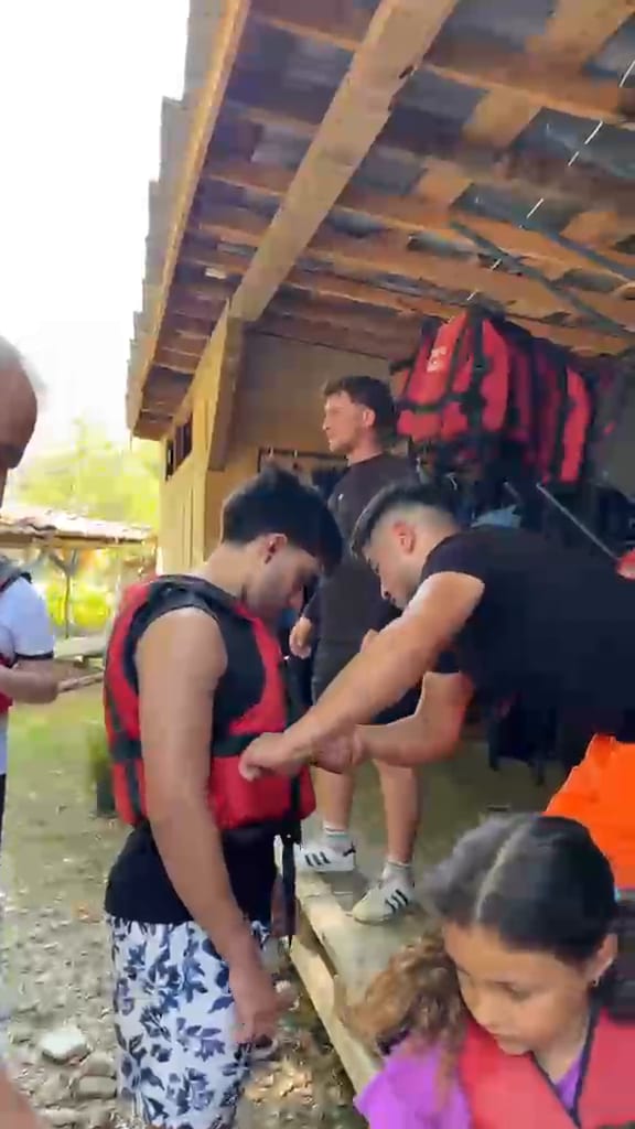 Rafting öncesi ahşap barınakta katılımcıların can yeleği kayışlarını ayarlayan eğitmen