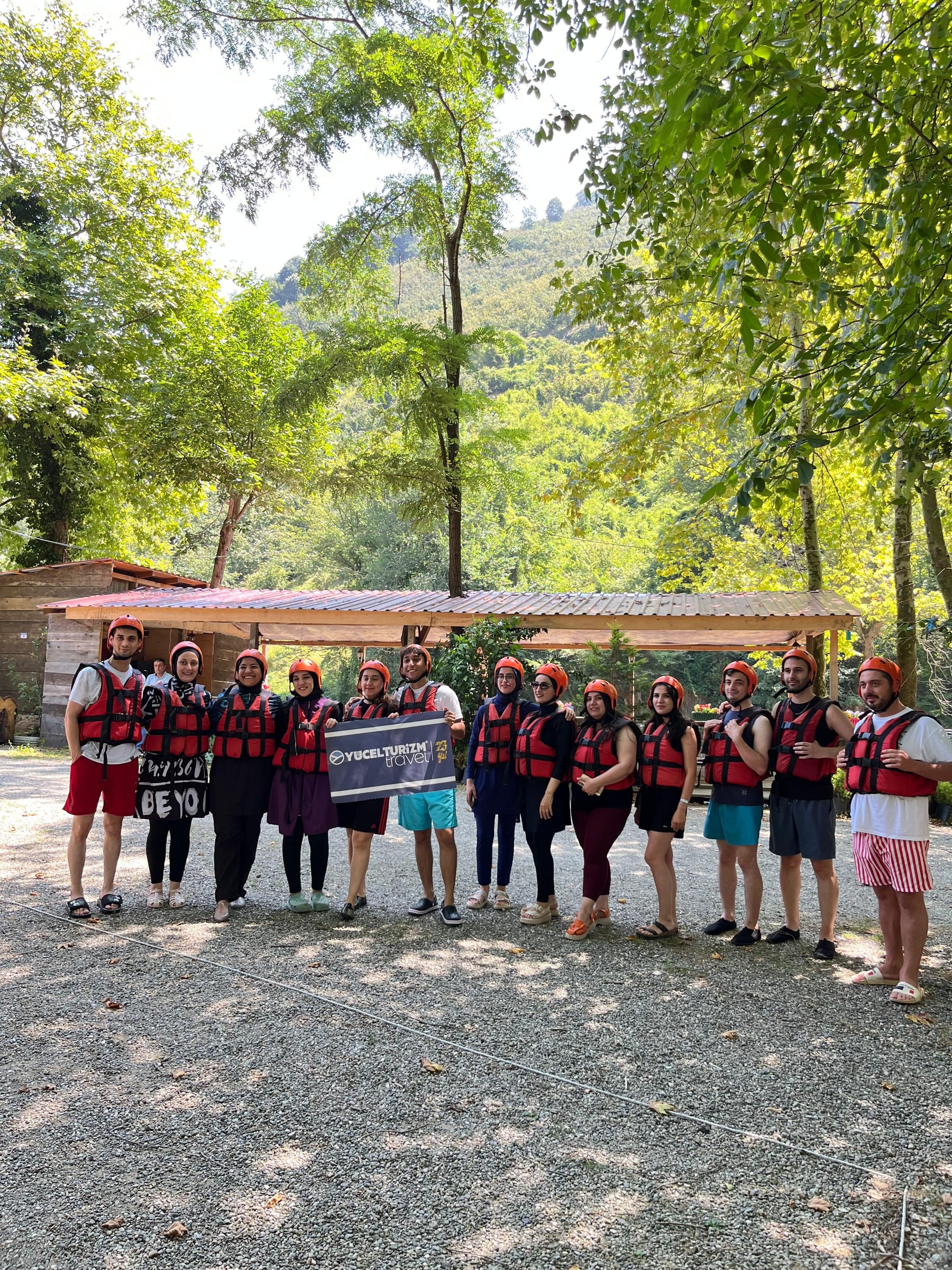 Grup rafting organizasyonunda can yeleği giymiş şirket ekibinin siyah pankart tutarak verdiği toplu poz