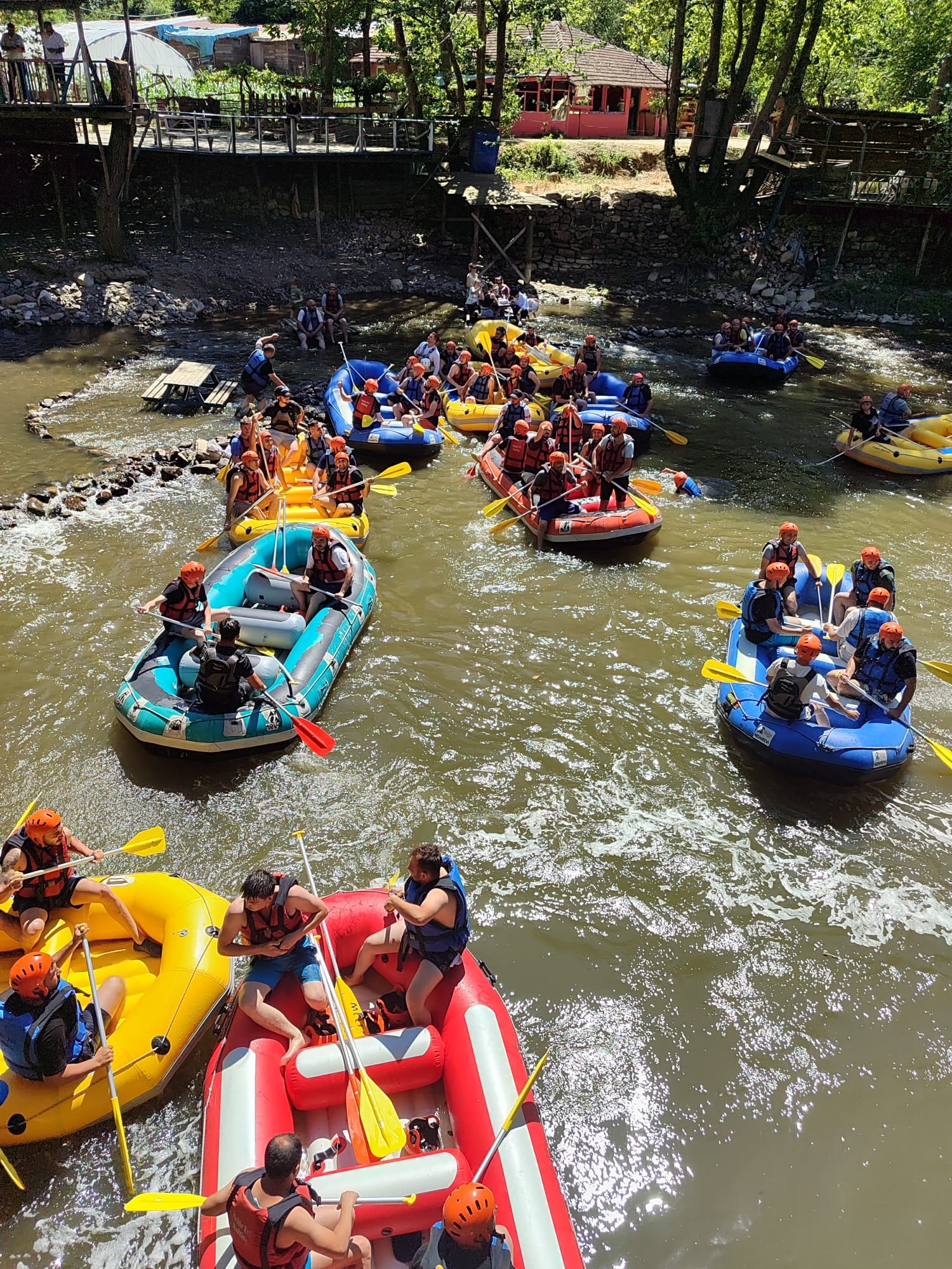 Düzce rafting turunda Melen Çayı üzerinde yan yana ilerleyen mavi, turkuaz ve sarı rafting botları ile kalabalık katılımcı grubu