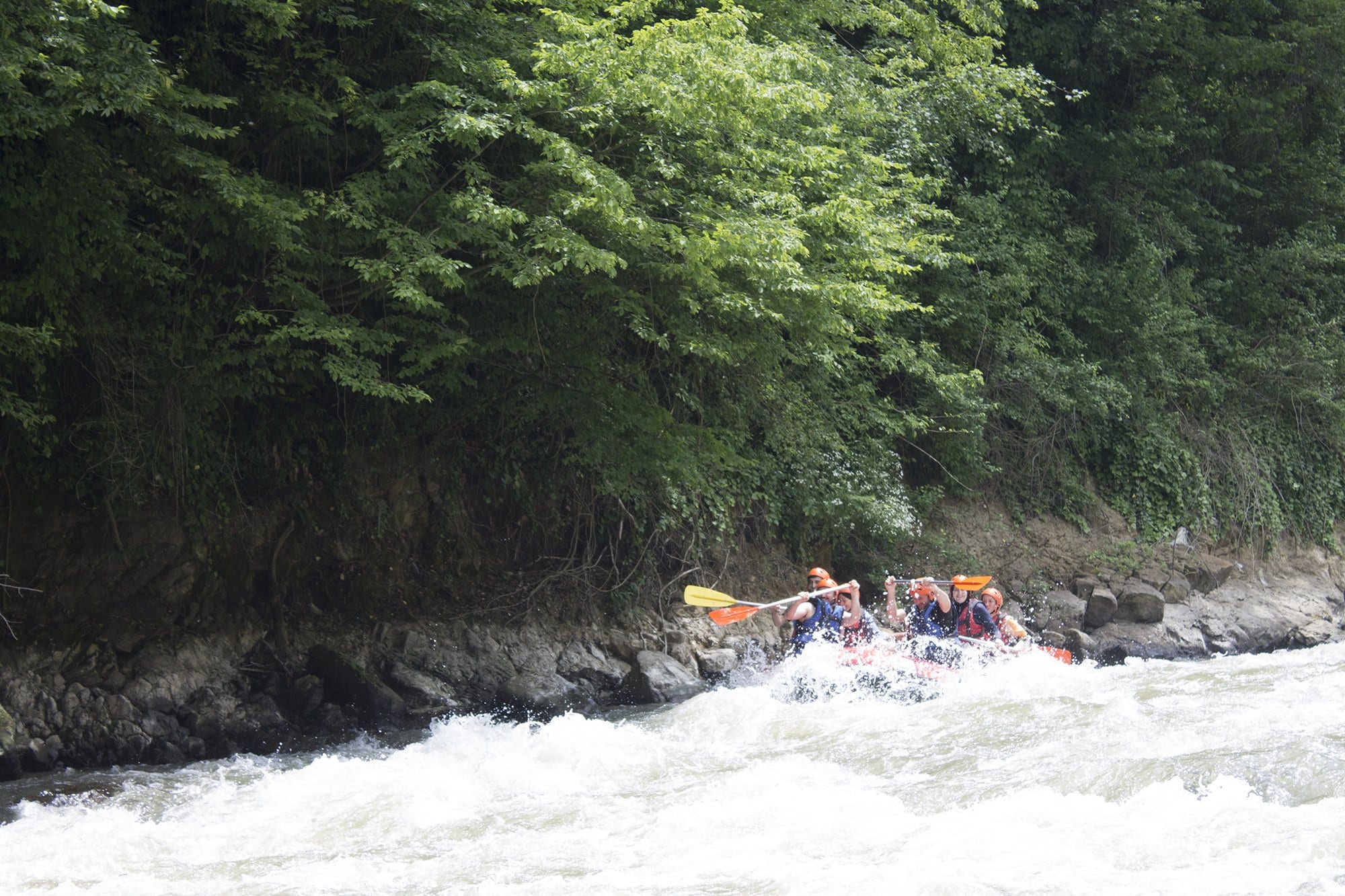Melen Çayı rafting parkurunun ormanla kaplı dik kaya duvarı önünde uzaktan görünen tek rafting botu