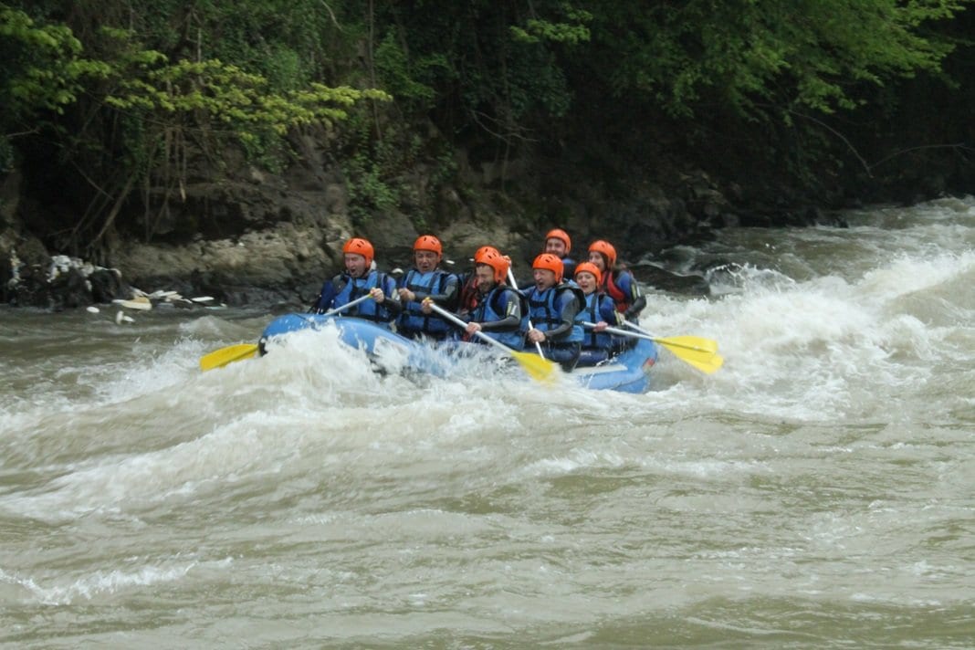 Melen Çayı rafting turunda sarı küreklerle karşıdan gelen mavi bot ve turuncu kasklı yedi kişilik ekip